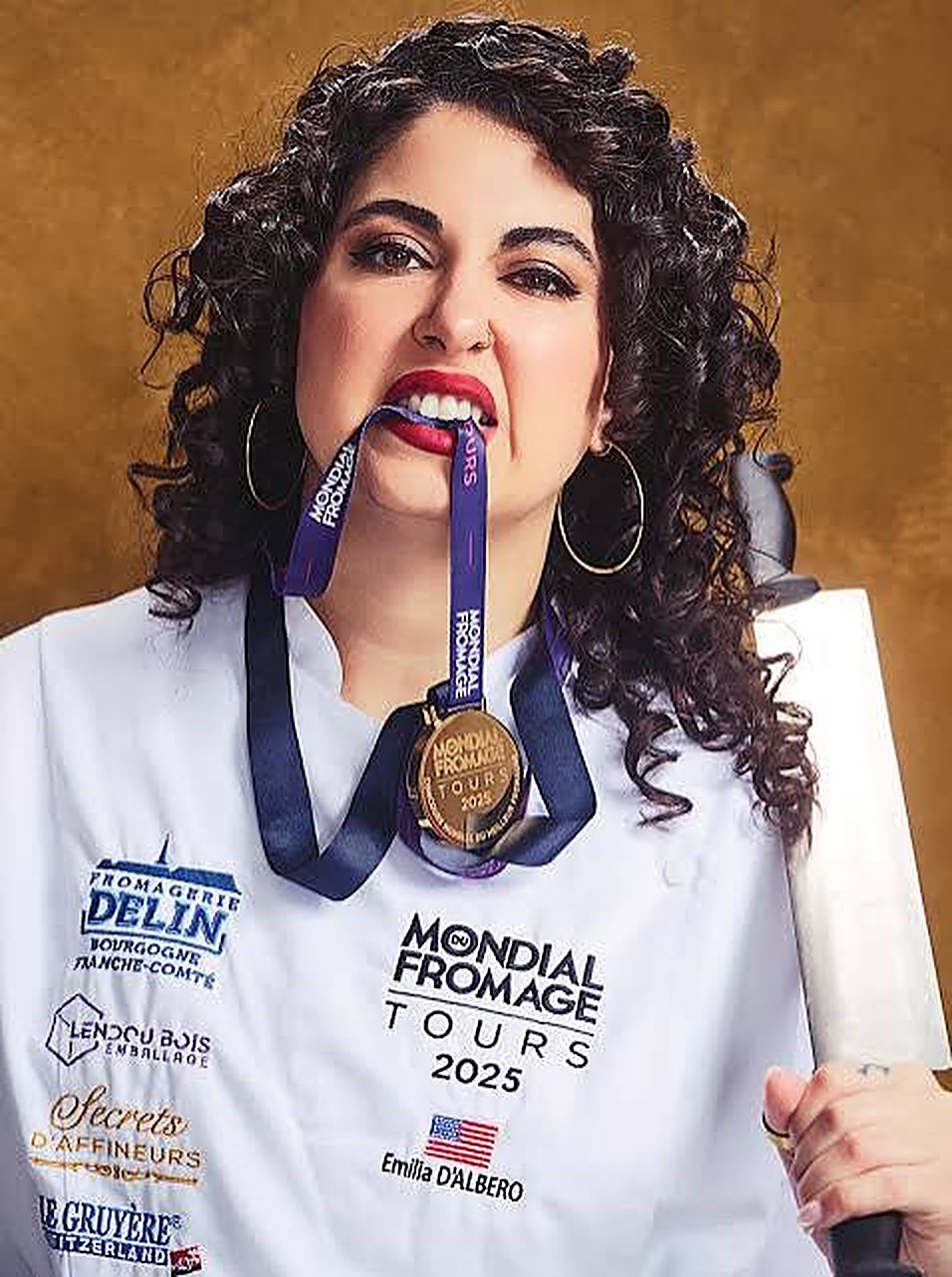 Emilia in her chef's whites, biting her Mondial du Fromage gold medal