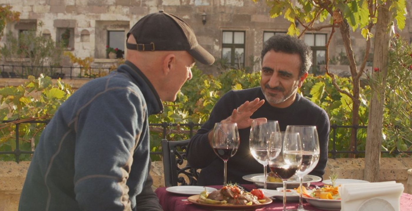 Todd Carmichael and Hamdi Ulukaya talking over dinner on a terrace in Turkey